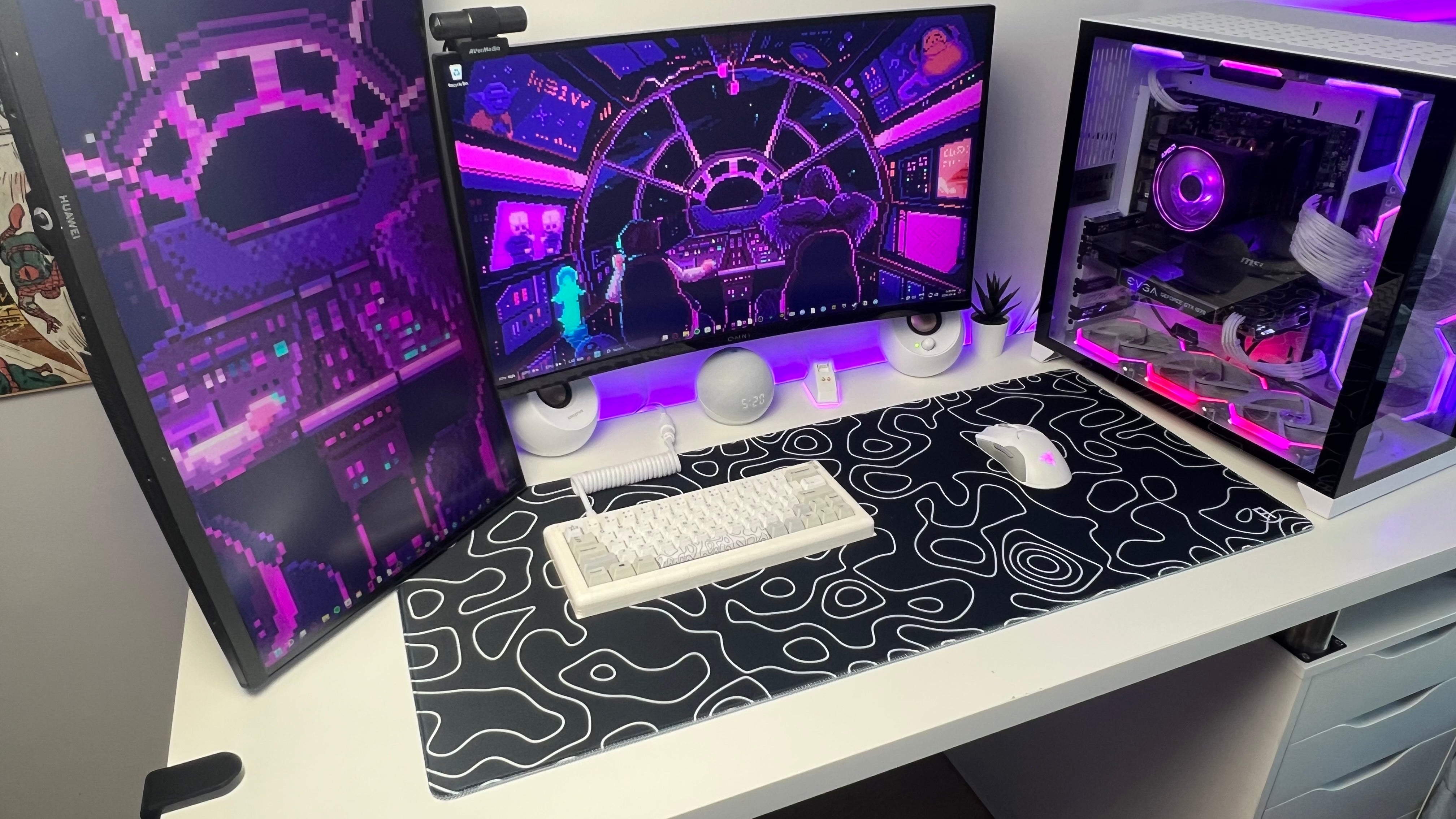 Computer setup with multiple monitors on a desk, featuring a black and white patterned mouse pad. Balck topography deskpad side view from gaming setup.