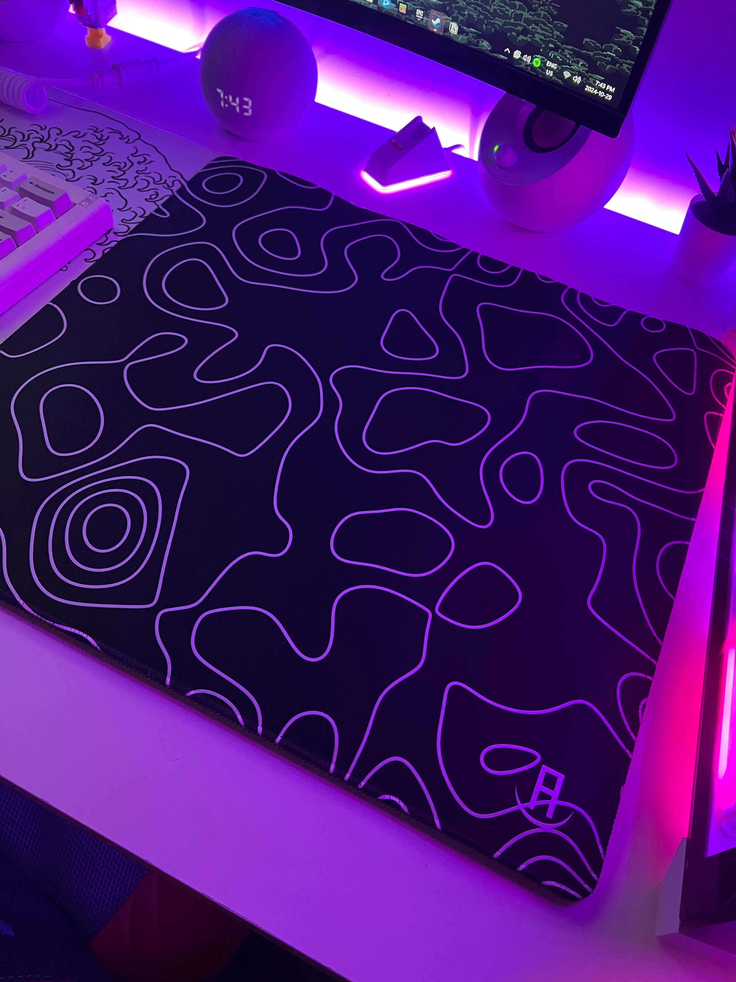 Black gaming mousepad with white abstract patterns on a desk with purple lighting